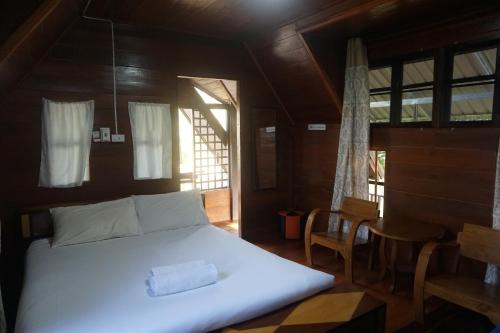 a bedroom with a bed and a table and windows at Samnaree Garden House in Ban Phae Mai