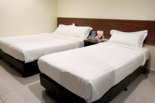dos camas sentadas una al lado de la otra en una habitación en Maple Inn, en Kuala Lumpur