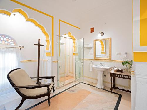 a bathroom with a chair and a shower and a sink at Alsisar Mahal- Heritage Hotel in Alsīsar