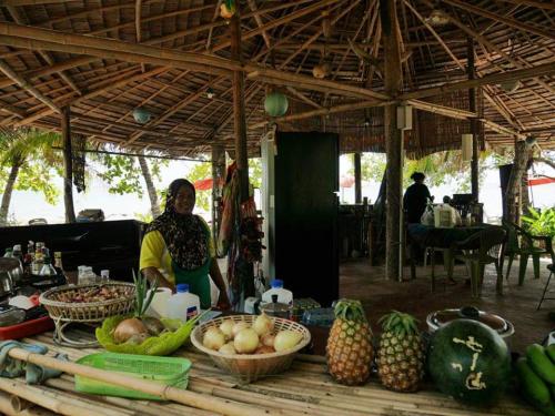 a woman standing in front of a table with fruits and vegetables at Dugong Koh Sukorn in Ko Sukon