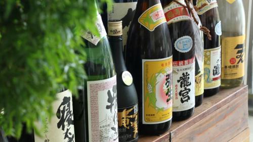 a row of wine bottles sitting on a wooden shelf at Rest and Lodge Syou in Amami