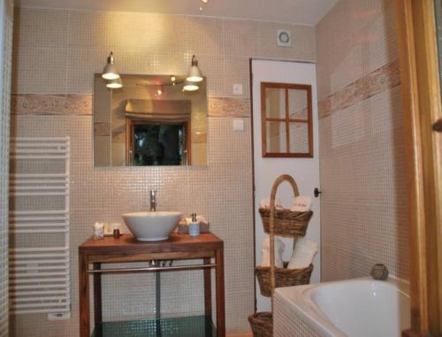 a bathroom with a sink and a mirror and a tub at Chambres d'hôtes La Petite Flambée in Le Tronquay