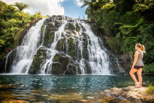 a woman standing on a rock in front of a waterfall at Riverside Accommodation in Karangahake