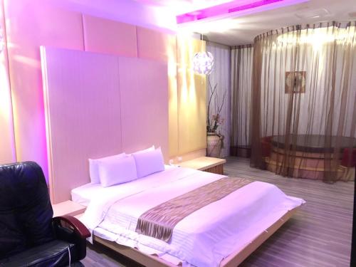 a bedroom with a large white bed and a chair at Idee SPA Motel in Yangmei