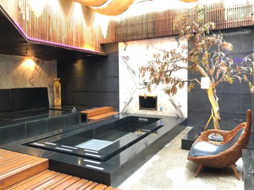 a large black tub in a room with a chair at Idee SPA Motel in Yangmei