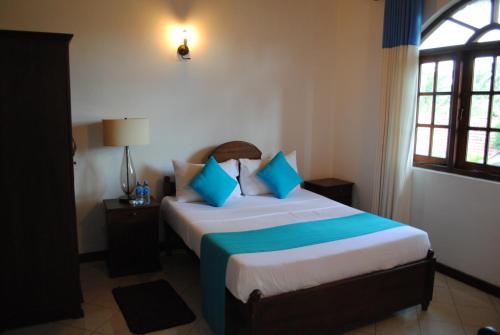 فيلا سوجيواني في نيجومبو: غرفة نوم مع سرير ووسائد زرقاء وبيضاء