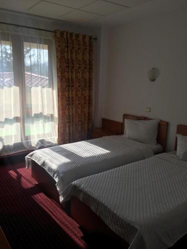two beds in a hotel room with a window at Pensiunea Tempo Sovata in Sovata