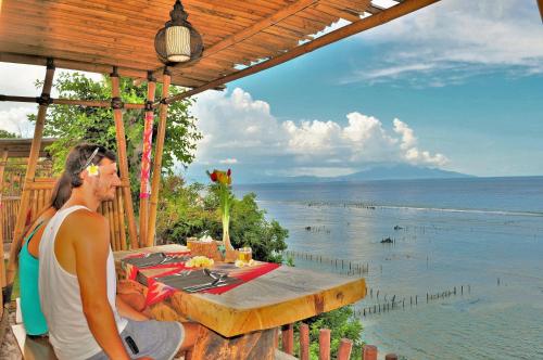 a man sitting at a table looking at the water at Ocean Terrace Suite And Spa Luxury in Nusa Penida
