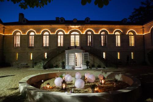 un bâtiment avec une fontaine devant lui la nuit dans l'établissement Chambres d'Hotes La Chartreuse des Eyres, à Podensac