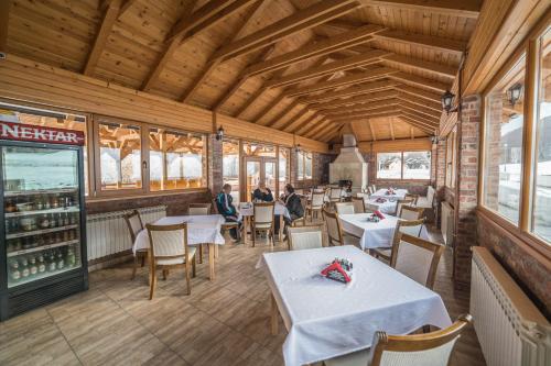 a restaurant with white tables and chairs and windows at Vila "Maglić" in Tjentište