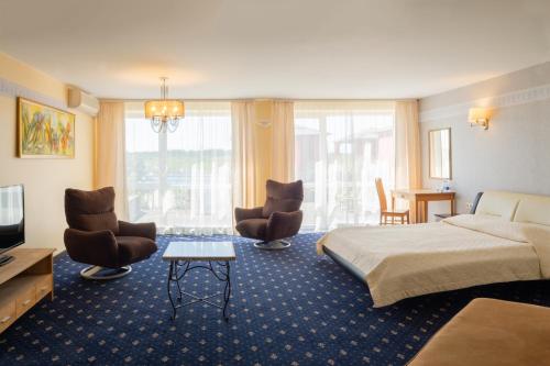 a hotel room with a bed and two chairs at Villa Alicante & SPA in Zujūnai