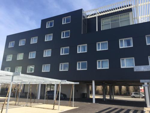 a black building with scaffolding in front of it at HOTEL LES 3 VALLÉES in Saran