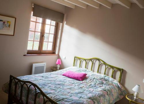 een slaapkamer met een bed met een roze kussen erop bij Gîte de La Ferme des Crins Blancs in Hazebrouck