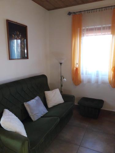 a living room with a green couch and a window at Mátyásmadár Vendégház in Tard