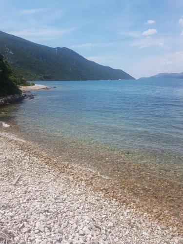 a rocky beach with the ocean and mountains in the background at Guesthouse Klara in Duba Stonska