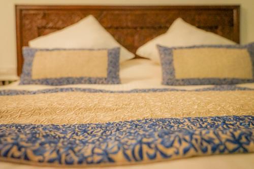 a bed with two blue and white pillows on it at Le Grand Alcazar - Riad in Fès