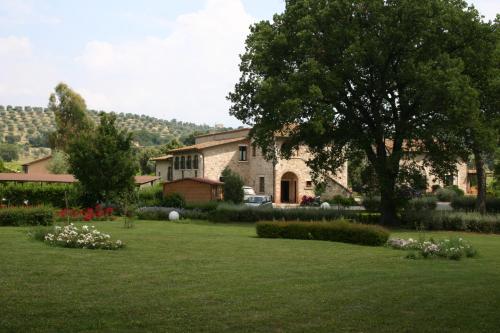 a large stone house with a yard with flowers at Villa Acquaviva Wine Resort in Montemerano