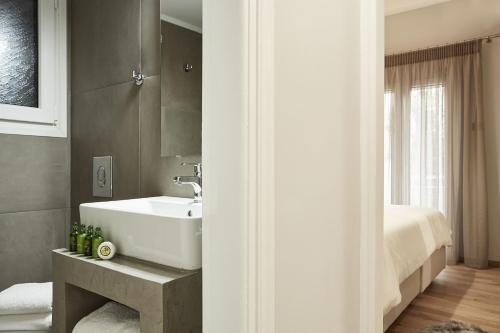 ein Bad mit einem weißen Waschbecken und einem Bett in der Unterkunft Charming Studio Apartment in Athen
