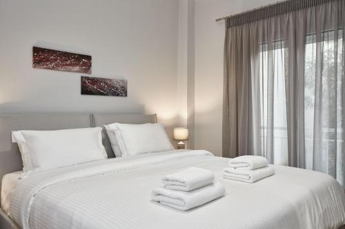 ein Schlafzimmer mit einem weißen Bett und Handtüchern darauf in der Unterkunft Charming Studio Apartment in Athen