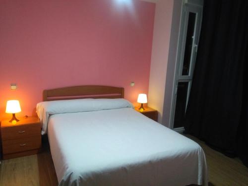 アランダ・デ・ドゥエロにあるAparthotel Ciudad de Arandaのベッドルーム(白いベッド2台、ランプ2つ付)