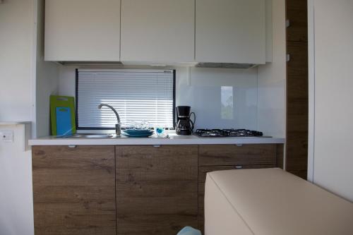 a kitchen with white cabinets and a sink and a window at Campeggio Europa Silvella in San Felice del Benaco