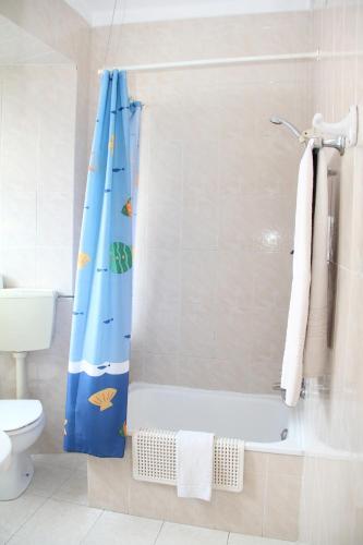 a bathroom with a shower with a blue shower curtain at Residencial Carvalho in Estremoz