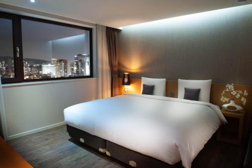 a bedroom with a large white bed and a window at Amanti Hotel Seoul in Seoul
