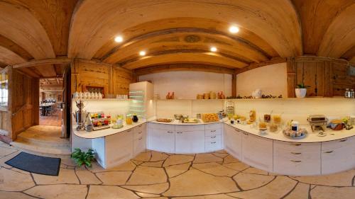a large kitchen with white cabinets and a vaulted ceiling at Landgasthof Büttel in Geisfeld