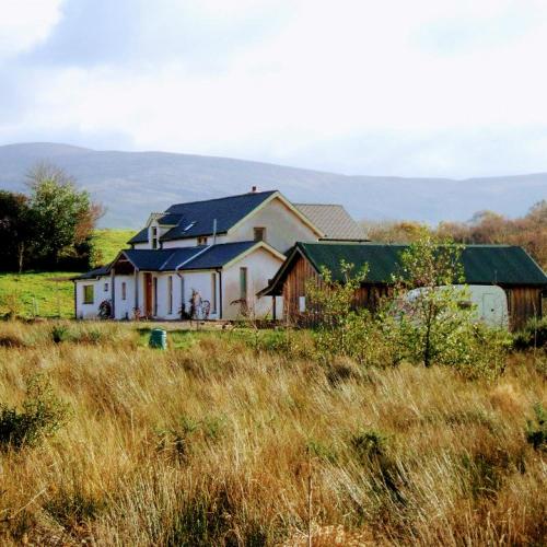 a white house with a green roof in a field at Kenmare Eco Lodge in Kenmare