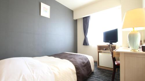 a hotel room with a bed and a desk and a television at Kotoni Green Hotel in Sapporo