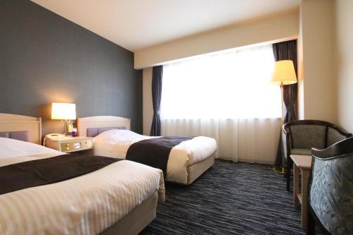 a hotel room with two beds and a window at Kotoni Green Hotel in Sapporo