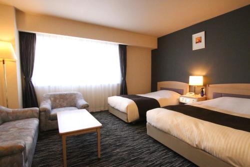 a hotel room with two beds and a couch at Kotoni Green Hotel in Sapporo