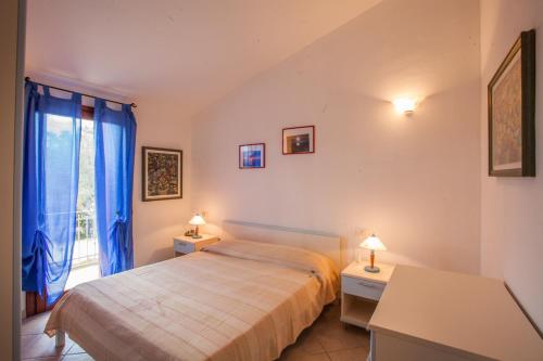 a bedroom with a bed and a window with blue curtains at Maestrale Flat - Klodge in Olbia