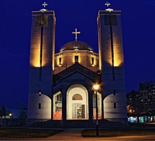 a church with a cross on top of it at night at Apartments & Dream Rooms in Niš