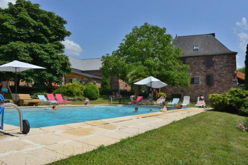 a swimming pool with chairs and umbrellas in a yard at La Ferme Du Duzou in Saint-Cyprien-sur-Dourdou