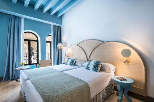 a bedroom with a large bed with a large headboard at Intelier Casa de Indias in Seville