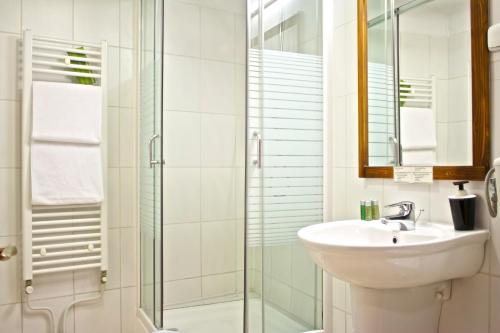 
a bathroom with a shower, sink, and mirror at Rembrandt Hotel in Bucharest
