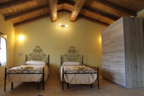 two beds in a room with wooden ceilings at Sa Domu Beccia B&B in Uras