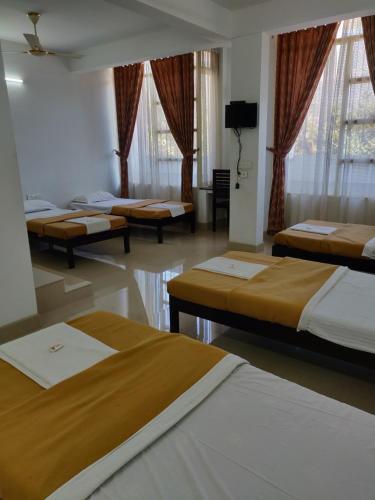 a group of beds in a room with windows at M3 Homes in Munnar