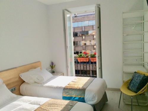 a bedroom with two beds and a window with a plant at Hostal Palacio Luna in Madrid