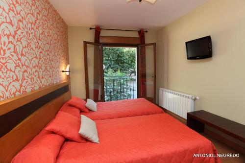 a bedroom with a bed with red sheets and a window at Hotel HC Sigüenza in Sigüenza