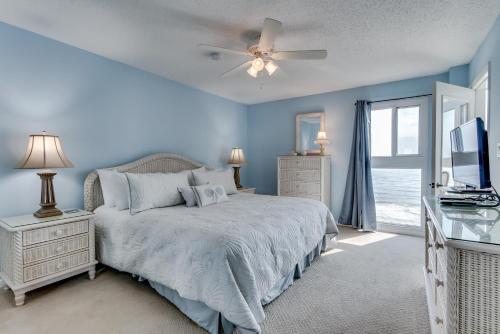a blue bedroom with a bed and a ceiling fan at Edgewater West #62 in Gulf Shores