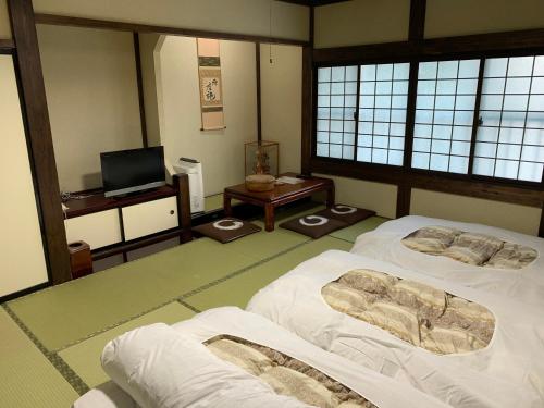 a room with two beds and a television in it at Ryokan Murayama in Takayama