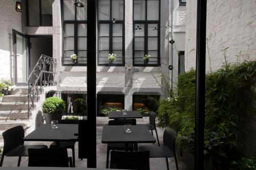 un patio avec des tables et des chaises dans un bâtiment dans l'établissement Hotel Neuvice, à Liège