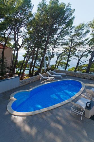 a large blue swimming pool with chairs and trees at Villa Paulina in Brela