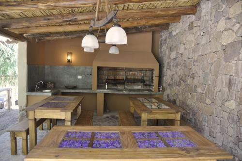 una cocina con mesas de madera y una pared de piedra. en Posada Don Juan en Tilcara