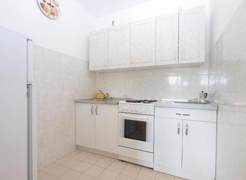 a white kitchen with white cabinets and a stove at Apartments Mira 1804 in Medulin