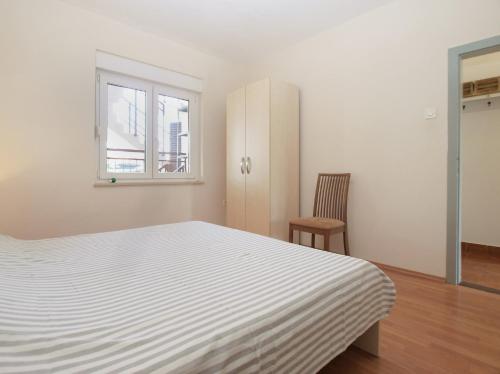 a white bedroom with a bed and a chair at Apartments Mira 1804 in Medulin