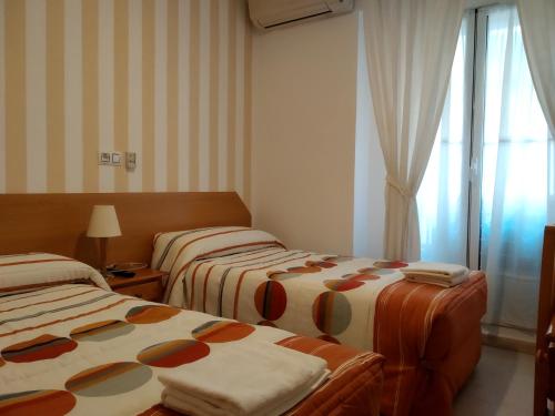 una camera d'albergo con due letti e una finestra di Pension Dominguez a Madrid