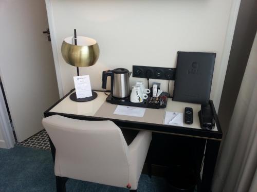 a desk with a coffee maker and a lamp on it at Best Western Hôtel Journel Paris Sud in Ris-Orangis